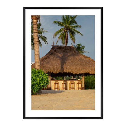 Photo of a thatched hut with palm trees on a beach