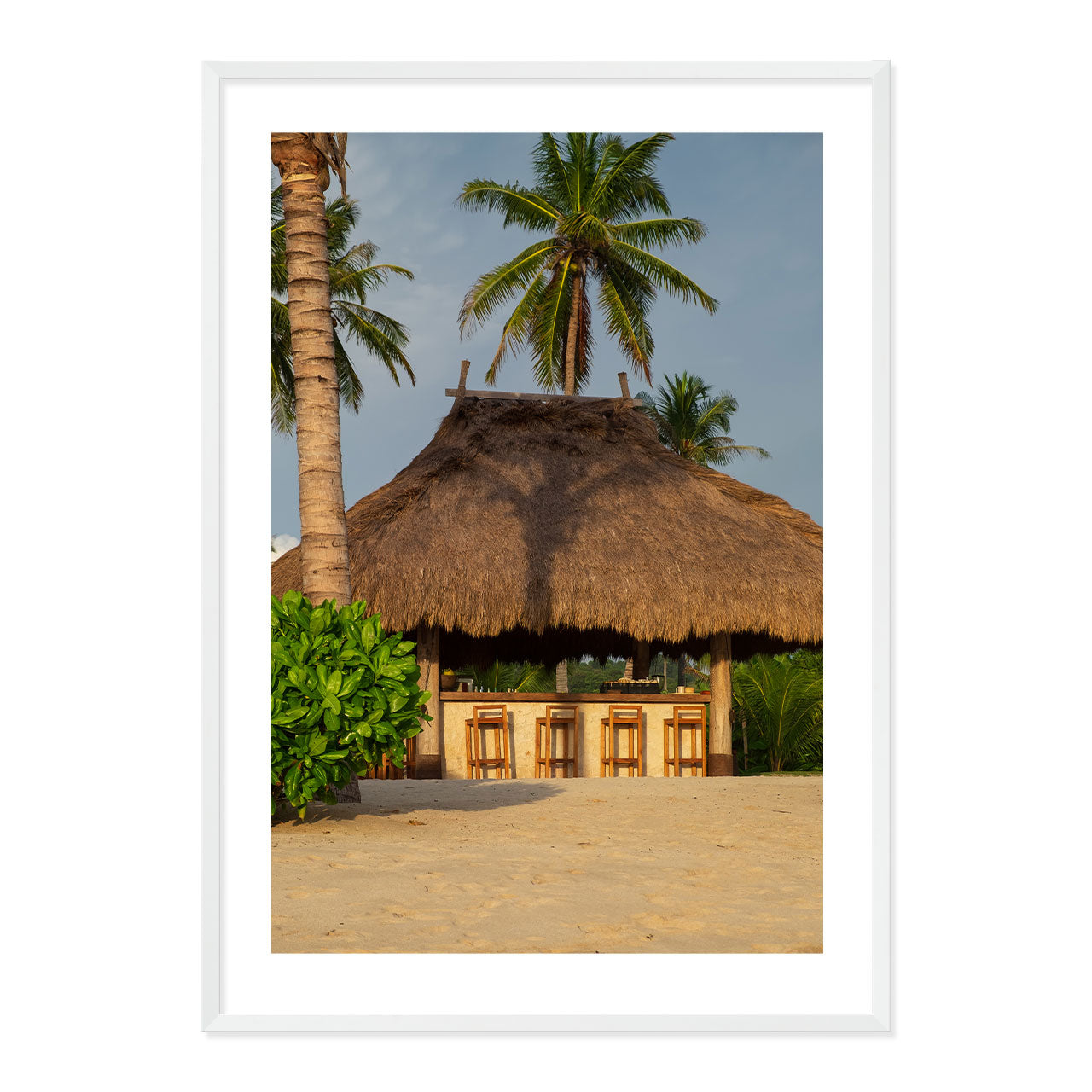 Photo of a thatched hut with palm trees on a beach