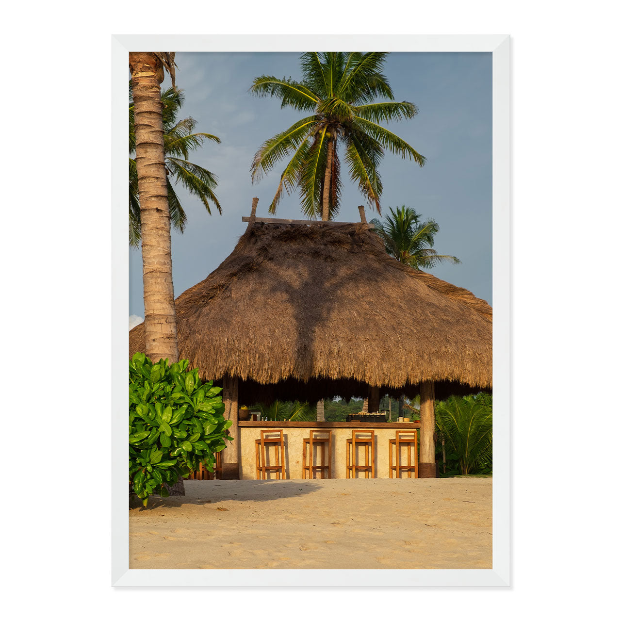 Photo of a thatched hut with palm trees on a beach