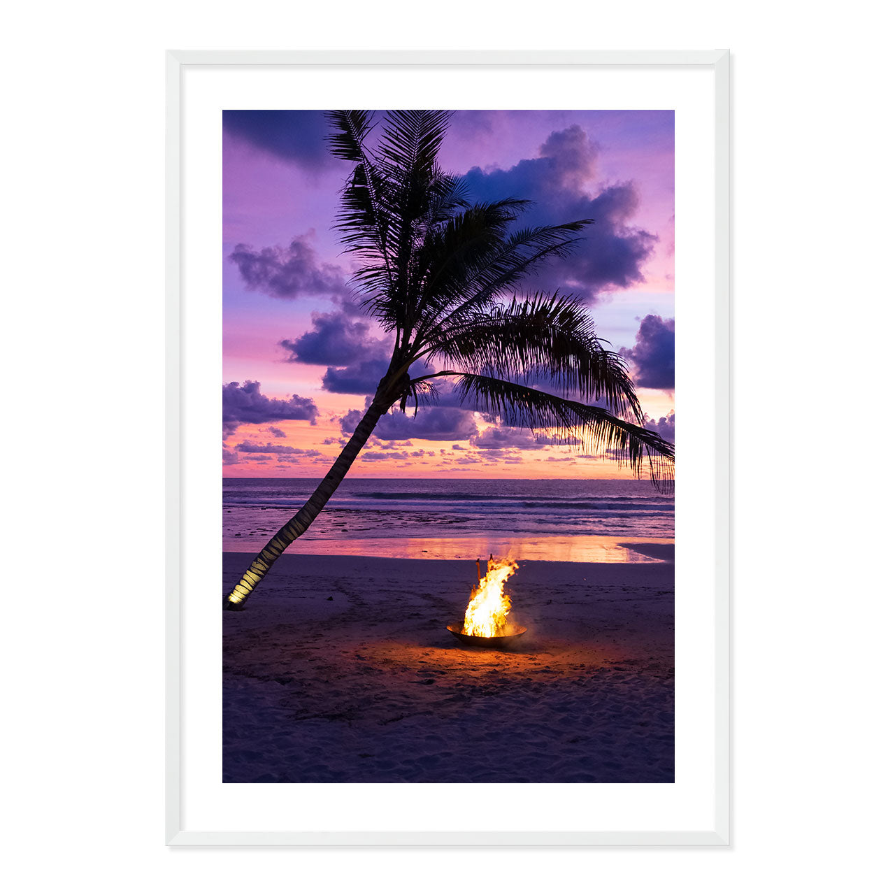 Framed photo of a fire pit by a palm tree on a beach with a sunset sky.
