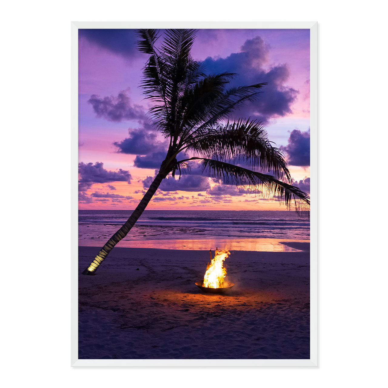 Framed photo of a fire pit by a palm tree on a beach with a sunset sky.