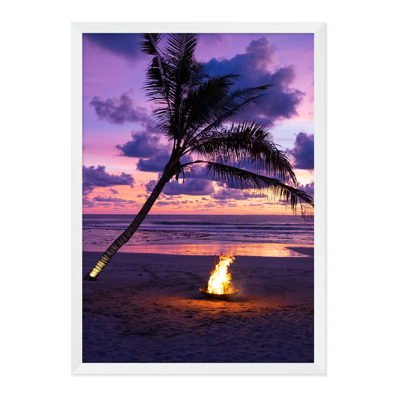 Framed photo of a fire pit by a palm tree on a beach with a sunset sky.