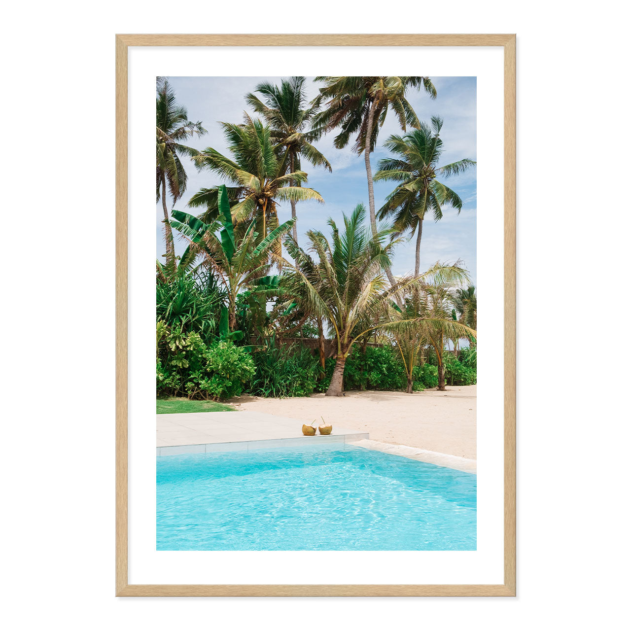 Framed artwork of coconuts by the pool with palm trees in the background.