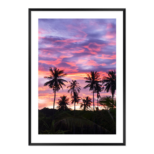 Framed artwork of palm trees against a vibrant purple and pink sunset sky.