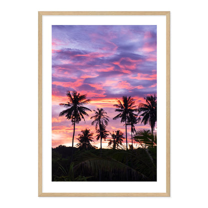 Framed artwork of palm trees against a vibrant purple and pink sunset sky.