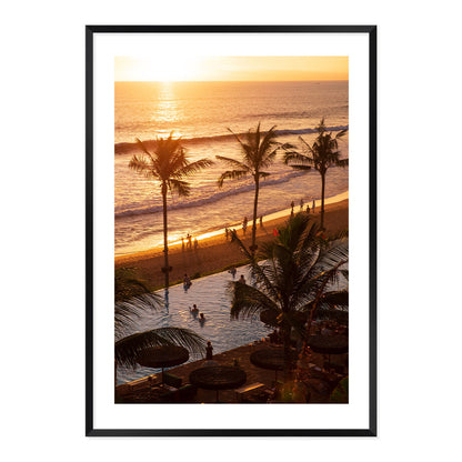 Framed artwork of a sunset over a beach with palm trees and people.