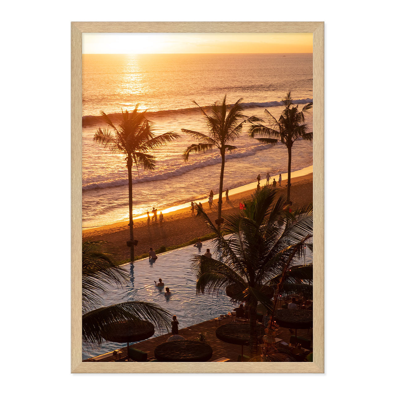 Framed artwork of a sunset over a beach with palm trees and people.