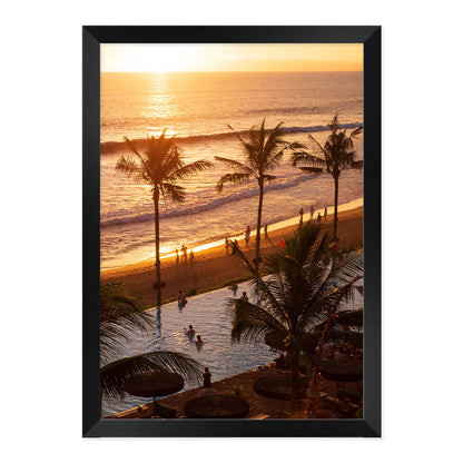 Framed artwork of a sunset over a beach with palm trees and people.