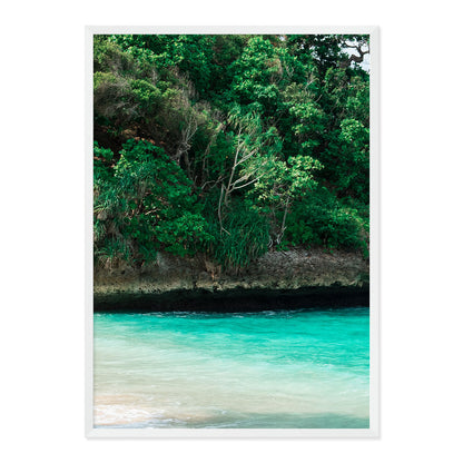 Framed artwork of a tropical landscape with greenery and turquoise water.
