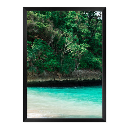 Framed artwork of a tropical landscape with greenery and turquoise water.