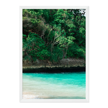 Framed artwork of a tropical landscape with greenery and turquoise water.